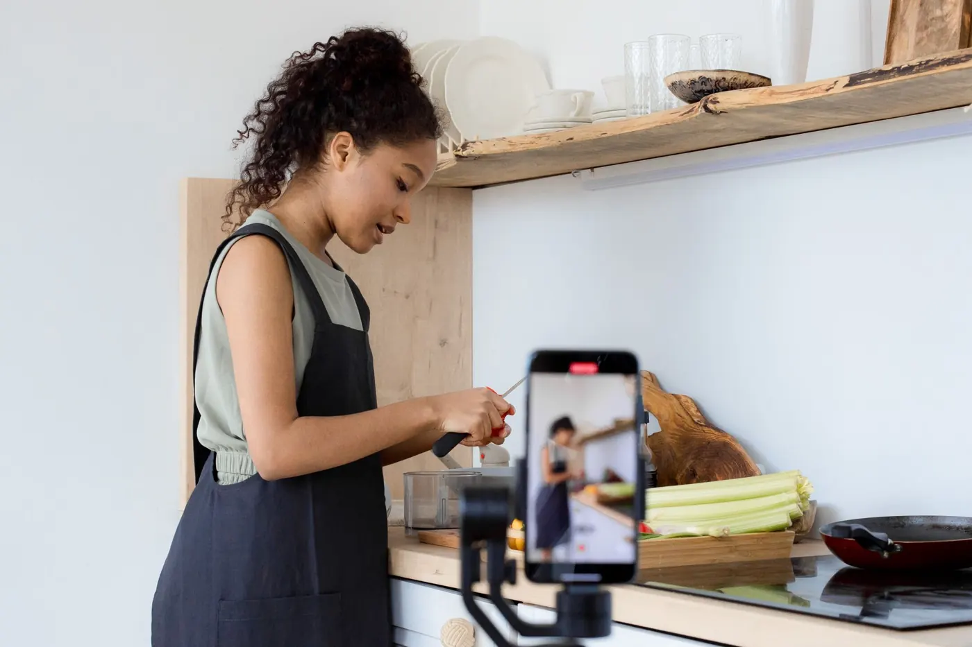 Empreendedora gravando um vídeo com o celular na cozinha do seu negócio