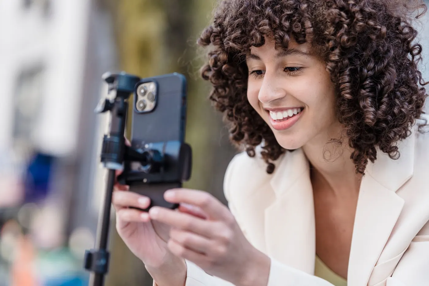 Mulher sorrindo enquanto confere no celular o vídeo que gravou